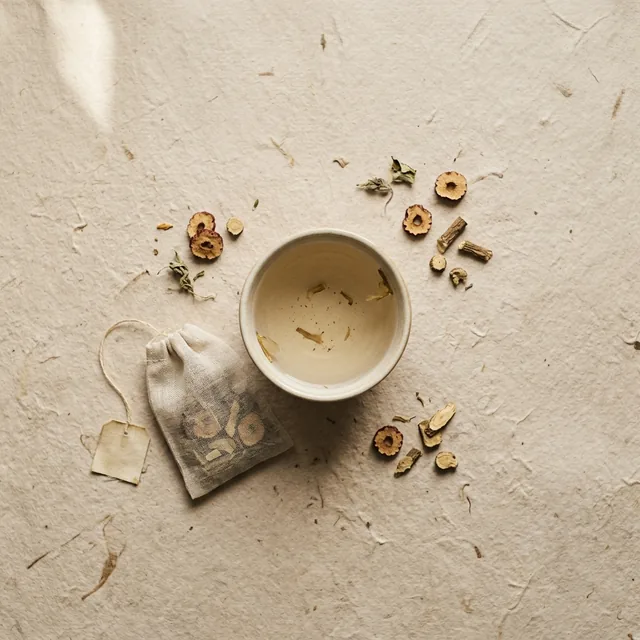 Gentle wellness tea, a sachet beside a cup on handmade paper
